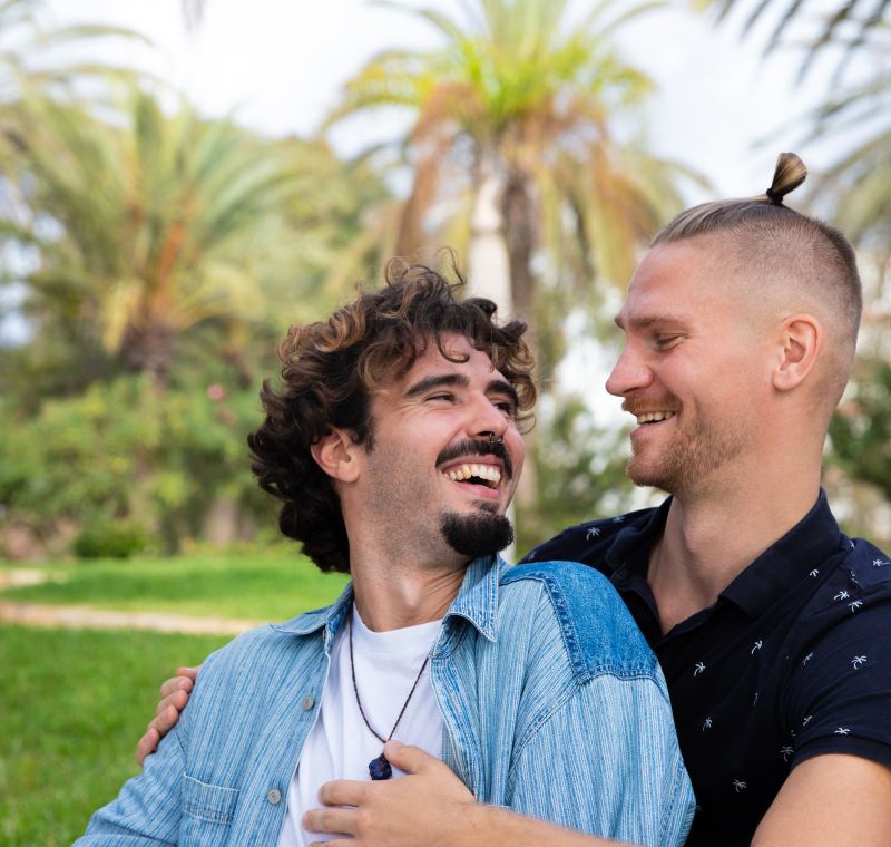 Couple d'hommes enlac�s et rieurs dans un parc